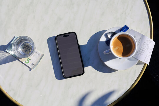 Top-down view of a marble table with a cup of espresso and smartphone