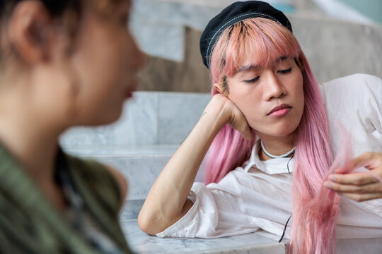 Sad person with pink hair looking down