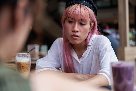 Thoughtful non binary person with friend at cafe