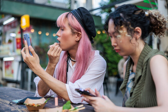 A non binary person with pink hair doing makeup
