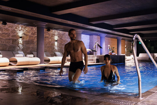 Serious couple going out of swimming pool at spa club