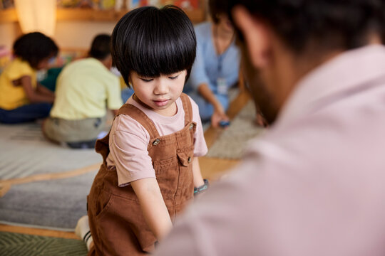 Cute boy playing with caretaker in daycare