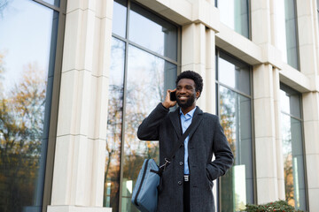 Smiley business consultant talking to client on smartphone outdoors