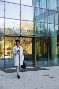 Bank teller texting on smartphone while exiting office building