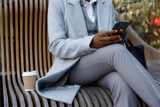 Partial view of trader working on phone outdoors and drinking coffee