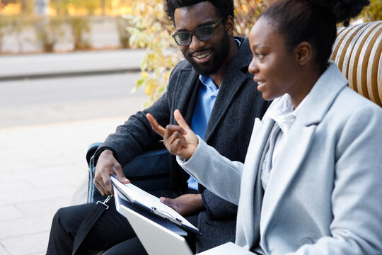 Business partners brainstorming while sitting on bench outdoors