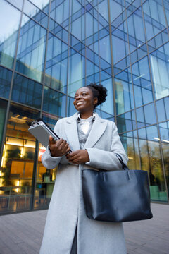 Graphic designer standing with laptop in plaza near office