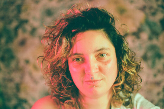 Smiling woman with curly hair posing in bedroom