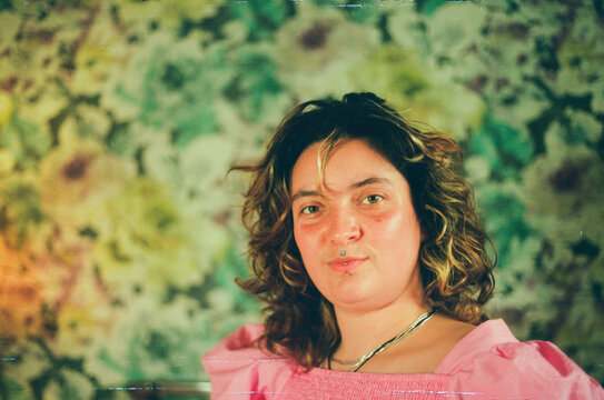 Young woman against floral wallpaper