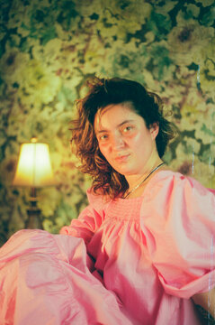 Young woman in pink dress in floral bedroom