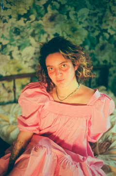 Young woman posing in pink dress in vintage bedroom