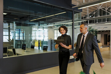 Formal business people walking and talking in modern office lobby