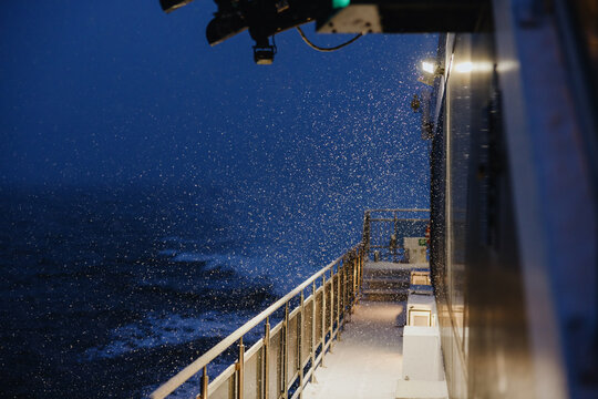 Snow falling on ship deck at sea during twilight