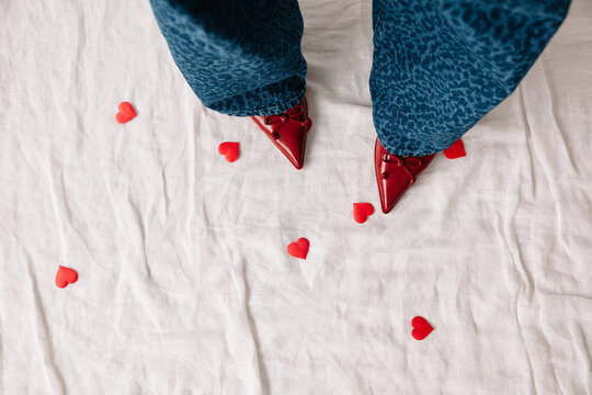 Bright red shoes stand out on white fabric with scattered heart
