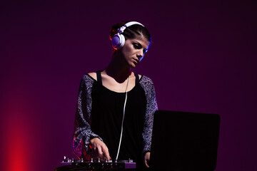 Girl DJ playing music on a mixer. Purple and red smoke in the background