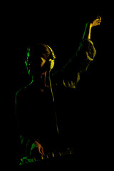 Female DJ with headphones on a mixer. Side lit silhouette of a girl playing techno music against...