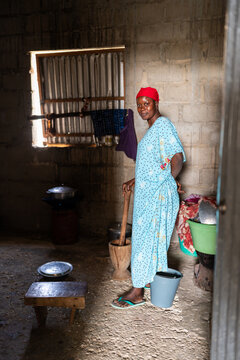 Senegalese woman holding wooden pestle standing in her kitchen