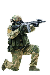 Kneeling soldier in full tactical gear aiming a rifle in isolated setting
