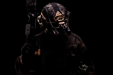Military operator in tactical gear with advanced equipment in dark environment