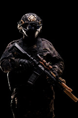 Naklejka premium Tactical soldier in full combat gear holding advanced rifle in low light