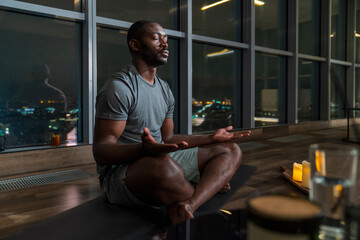 Man Meditating in a High-Rise Apartment at Night