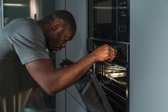 Man Adjusting Settings on a Modern Oven
