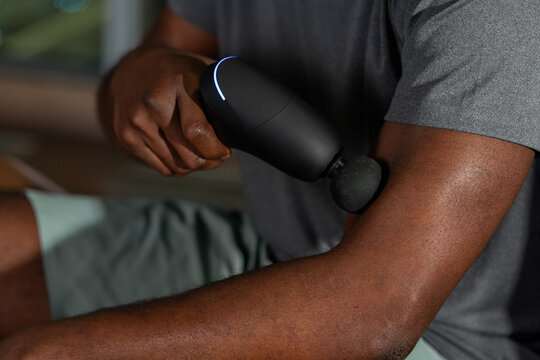 Man Using Massage Gun on Arm
