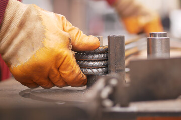 Worker shaping metal rods in a manufacturing workshop