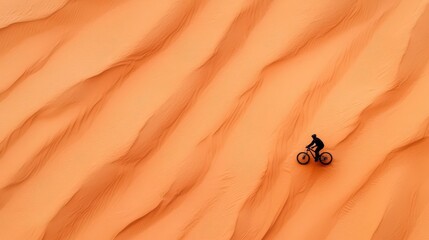 Obraz premium Aerial view of a cyclist in a vast desert, tiny human scale in an endless landscape, exploration concept