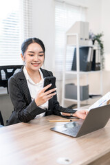 Portrait of beautiful young businesswoman using mobile phone working in modern work station.