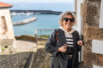 Tourist holding camera smiling in Cudillero, Asturias, Spain