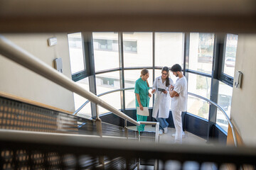 Medical team discussing patient data on digital tablet in hospital