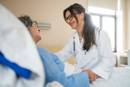 Female doctor comforting elderly patient in hospital bed