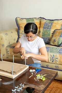 Artist using a knife to cut cardboard sheets for flower pressing