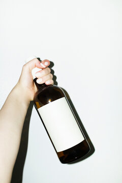 Hand holding glass wine bottle with etiquette & hard direct flash