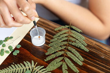 Hand of an unknown creative woman taking neutral ph glue with a brush