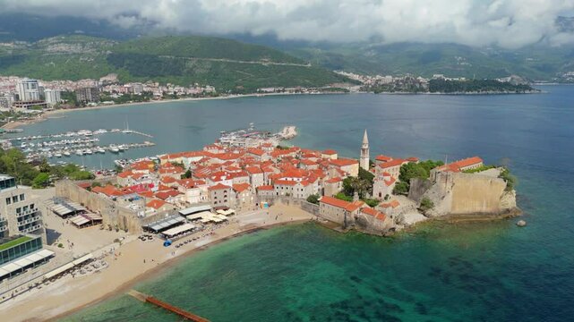 Aerial droen view Budva old town Stari harbour yachts Medieval Dubrovnik blue waters riviera mountains vacation holiday coastal Adriatic Mediterranean 