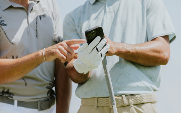 Golfers Reviewing Score on Mobile Phone at Sunny Course
