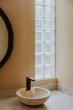 Elegant stone sink with modern faucet and glass block window