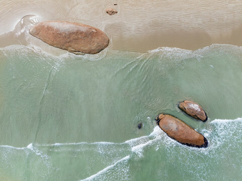 Large boulders embedded in a beach with waves breaking around them