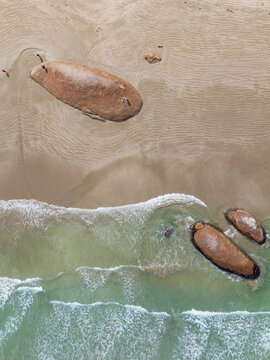 Large boulders embedded in a beach with waves breaking around them