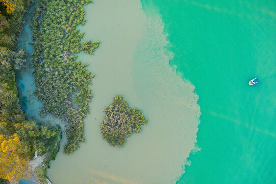 Small boat on green lake with cloudy water along the shoreline