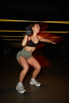 Woman exercising with dumbbell in a gym environment