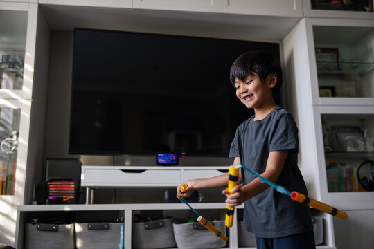 Young Boy Smiling and Playing With Toy Sticks in a Living Room