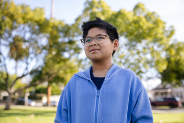Young Boy Outdoors in a Park with Glasses and a Blue Jacket