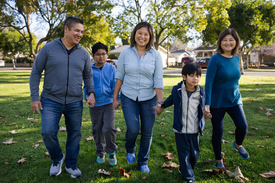Smiling Family Walking Together at Park on a Bright Sunny Day