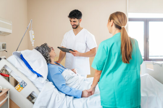 Medical team visiting and comforting elderly patient in hospital bed