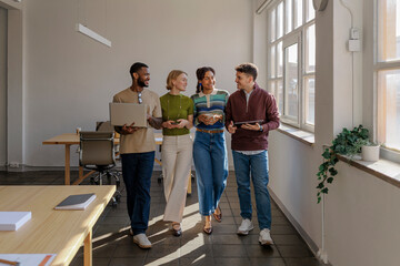 Diverse startup team walking and talking in modern office