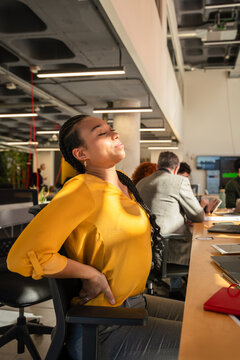 Woman in Office Stretching to Relieve Back Pain and Fatigue