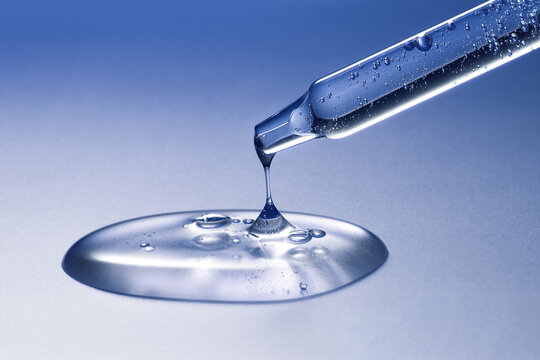 Glass pipette with anti-age moisturizing face serum on blue background